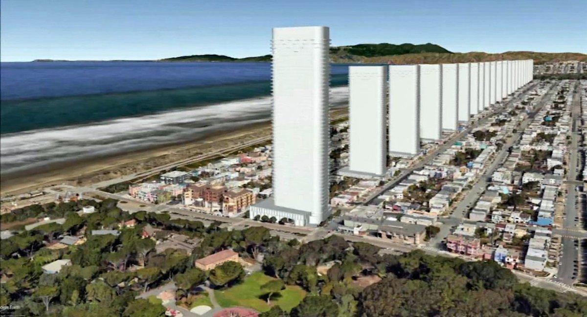 An aerial view of a coastal city with a row of tall white skyscrapers along the beachfront, adjacent to a dense residential neighborhood and green parkland.