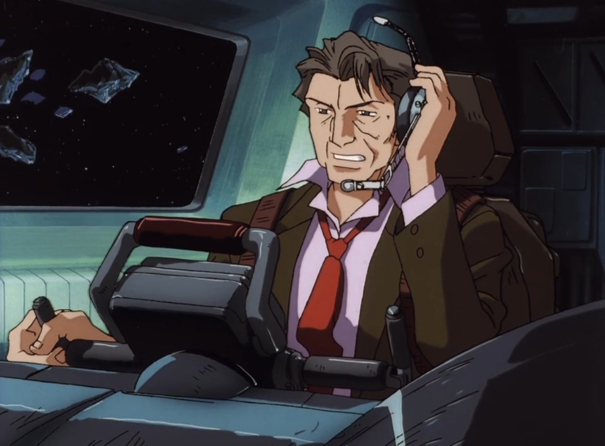 A man in a brown suit and red tie sits in a cockpit, wearing a headset and gripping a control stick, with a concerned expression as he looks out at stars and floating debris through the window.